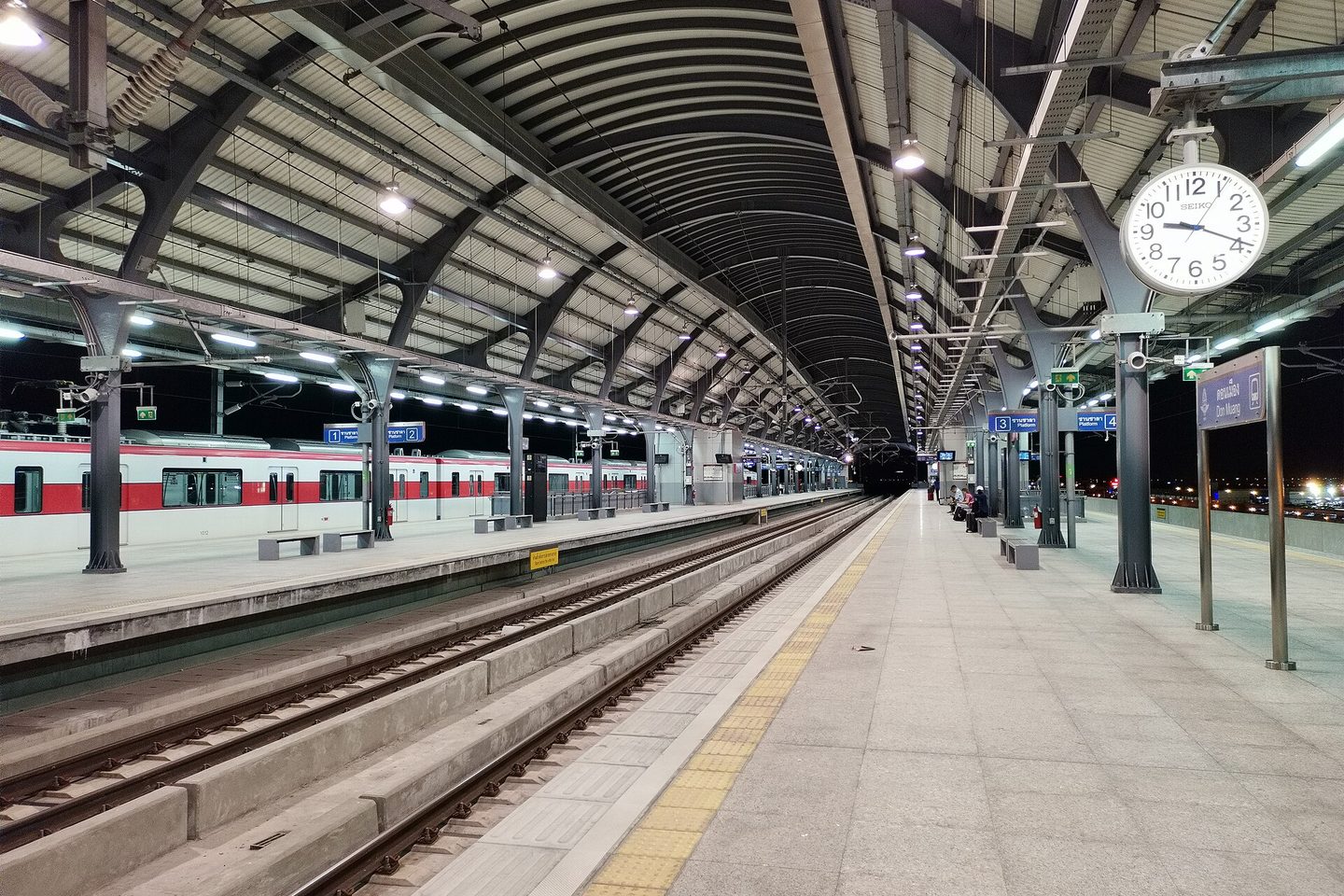 Platform at Don Mueang station on Bangkok's SRT Red Line at night, with a red and white train